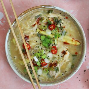 A bowl of gluten free chicken noodle soup with chopsticks.