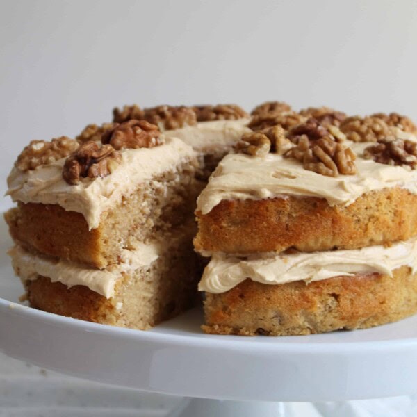 A gluten free coffee and walnut cake on a cake stand.