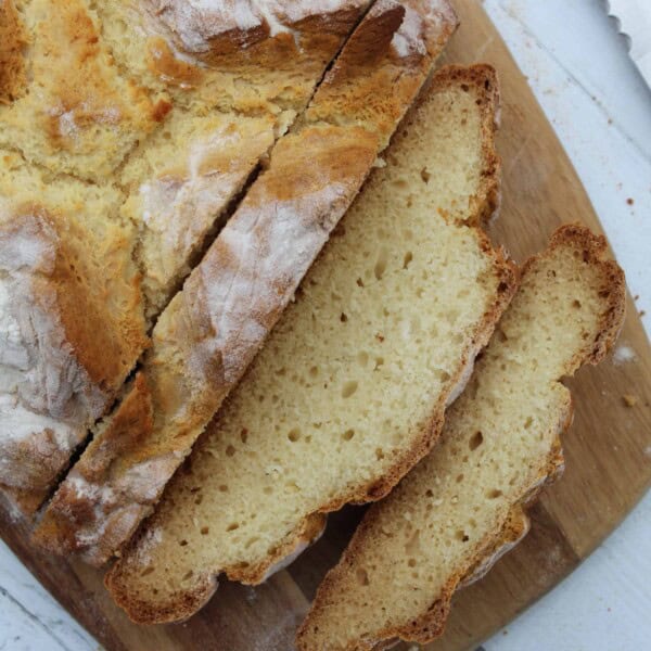 A gluten free soda bread sliced up on a wooden board.