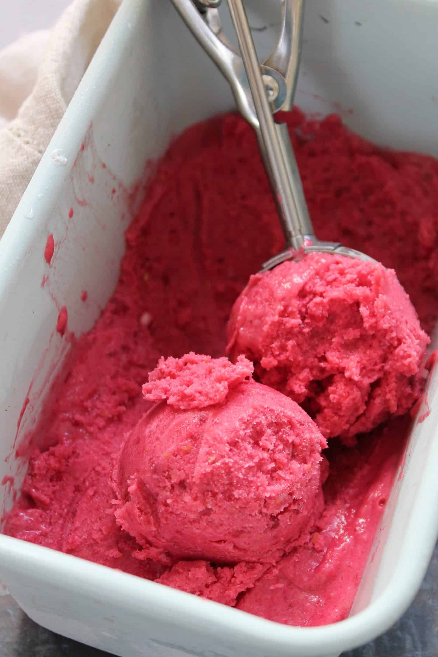 Scoops of frozen raspberry yogurt in a tub.