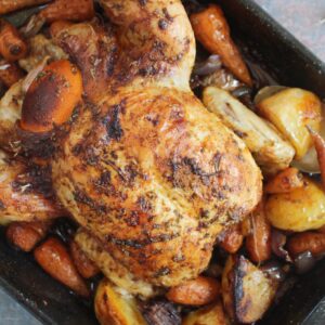 A pan with roast chicken and vegetables.