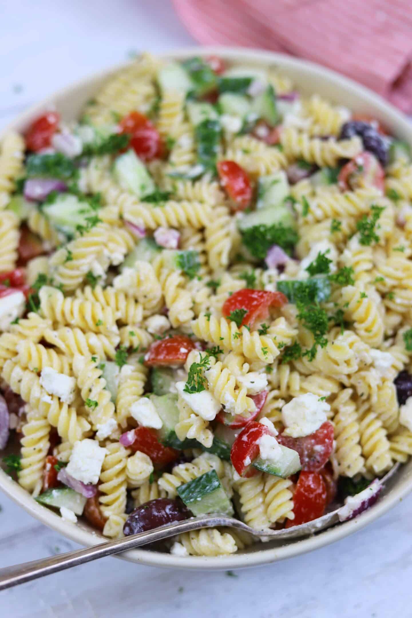 A close up of pasta salad with a Greek style dressing.