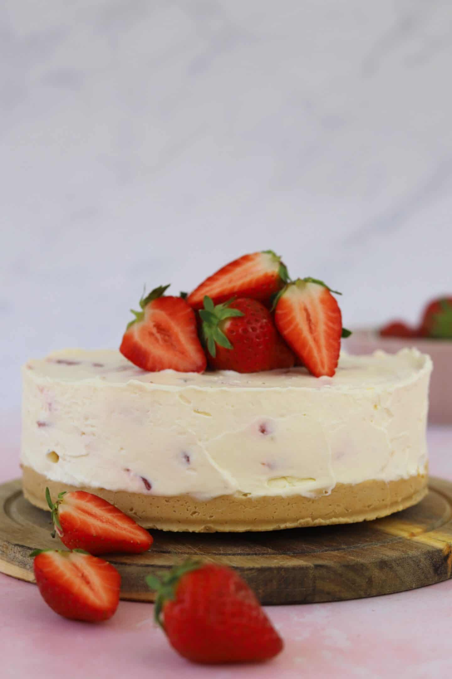 A strawberry cheesecake topped with strawberries on a chopping board.