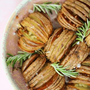 A bowl of air fryer hasselback potatoes with rosemary sprigs.
