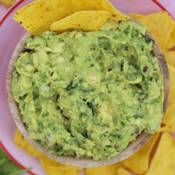A bowl of gluten free guacamole with tortilla chips.