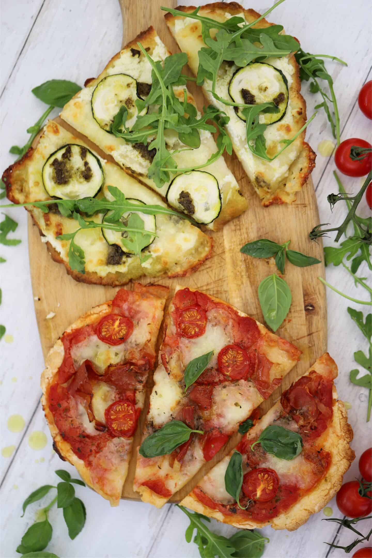 Two gluten free flatbread pizzas on a chopping board.