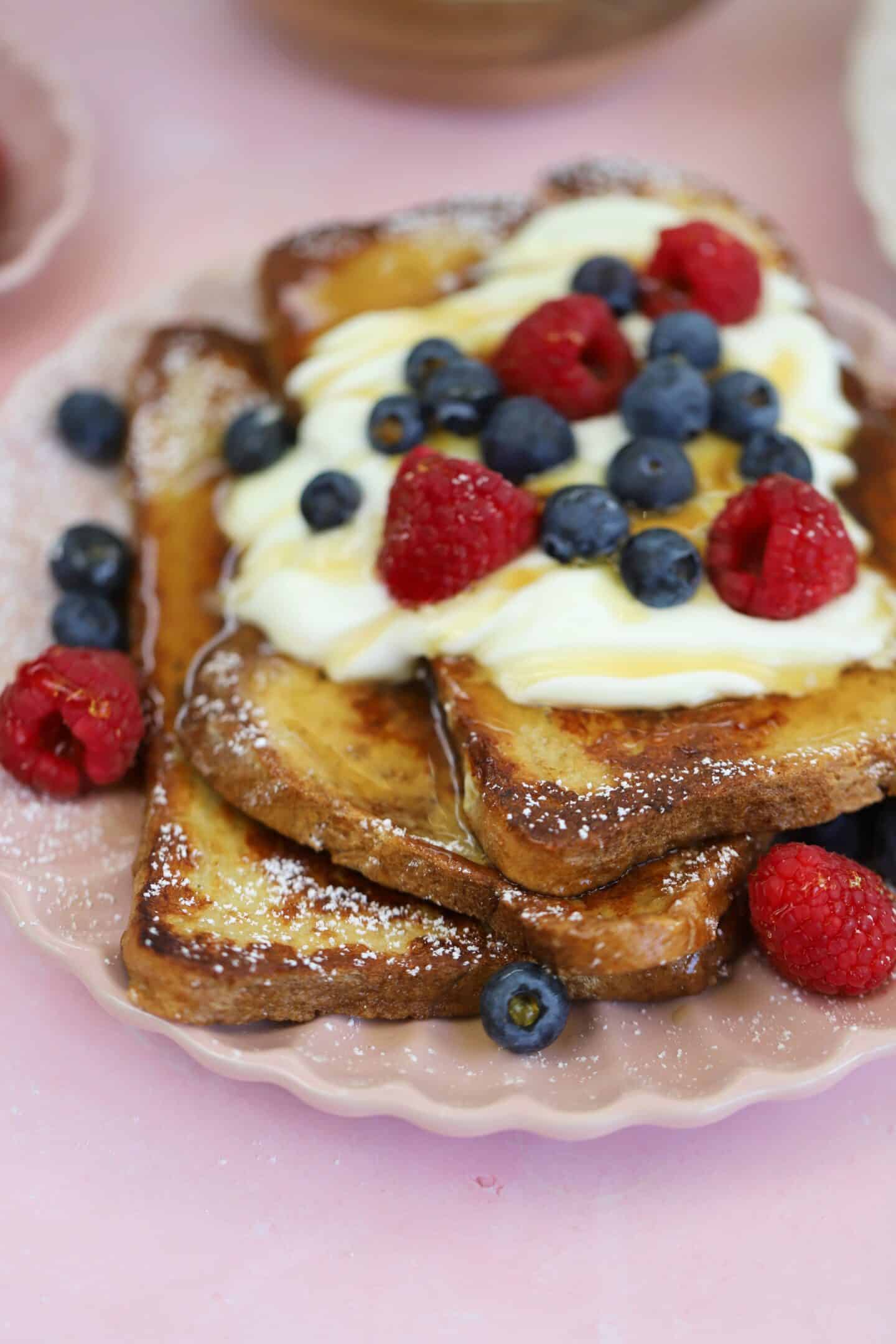 A plate of gluten free French toast with yoghurt and berries on top.