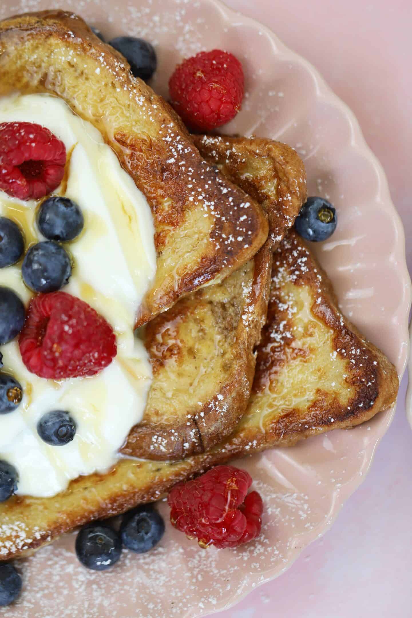 A plate of gluten free French toast with yoghurt and berries on top.