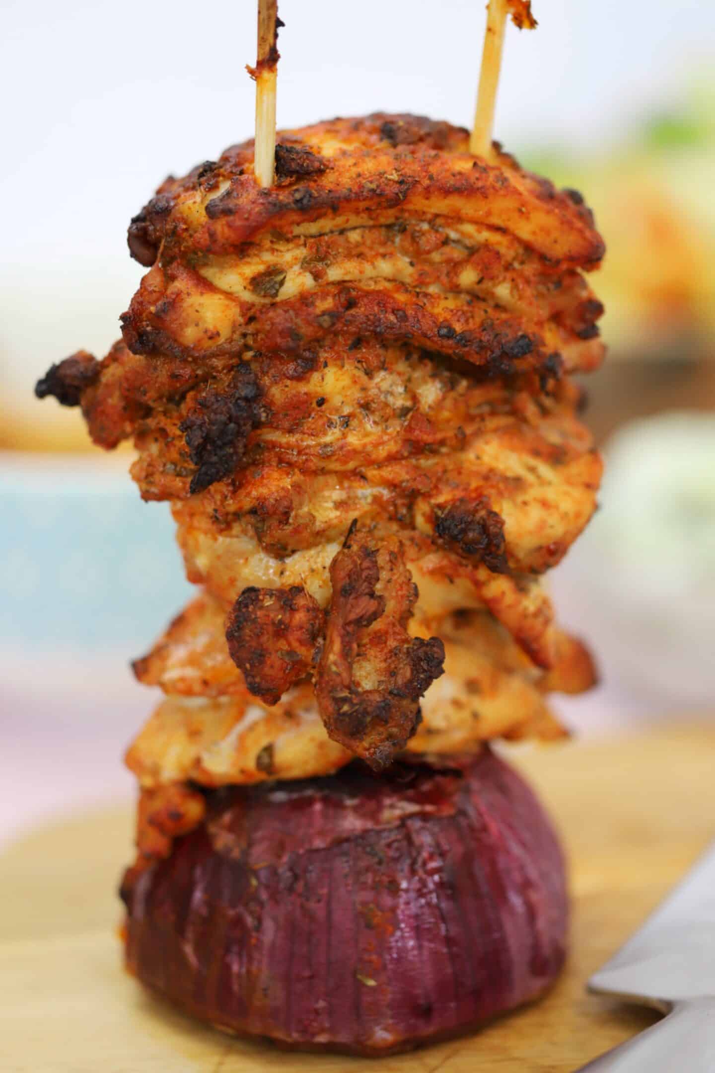 Gluten free gyros meat on two skewers, on top of half an onion.