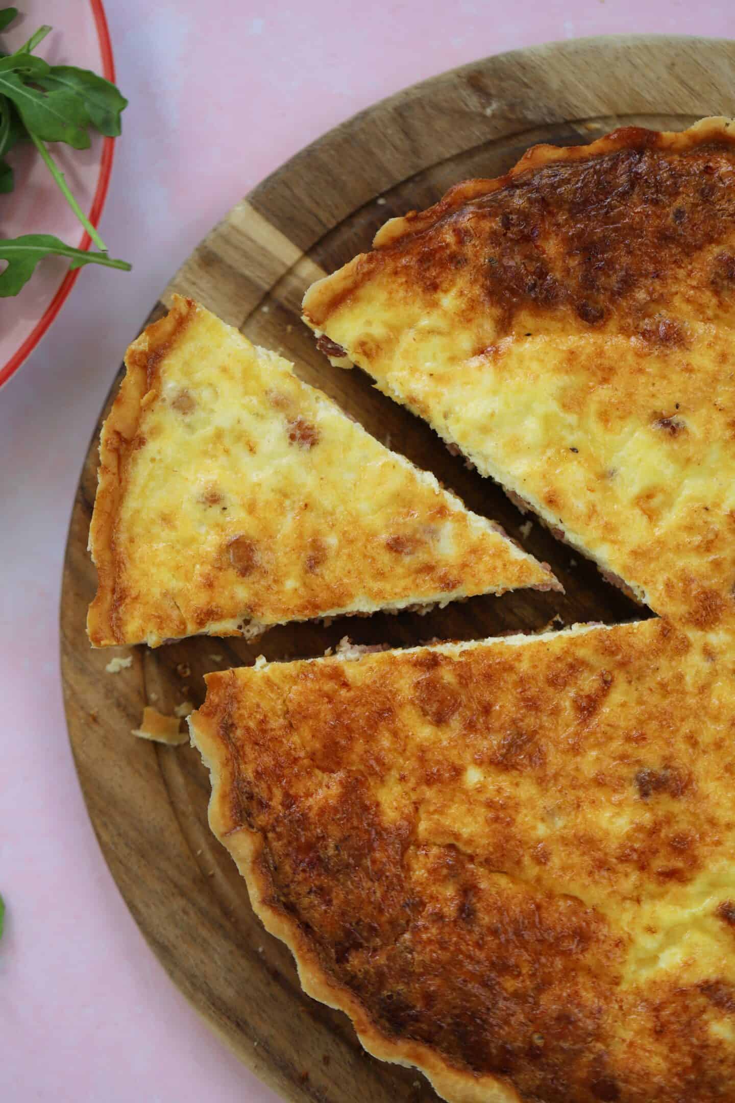 A gluten free quiche lorraine with a slice cut out.
