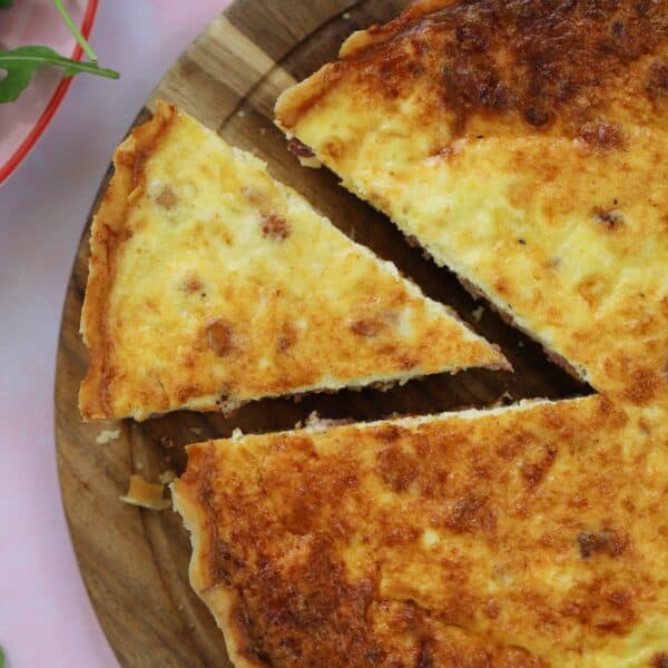 A gluten free quiche lorraine with a slice cut out.