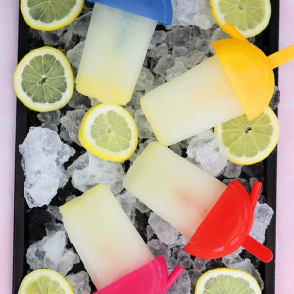 A tray of lemon ice lollies on ice with lemon slices.