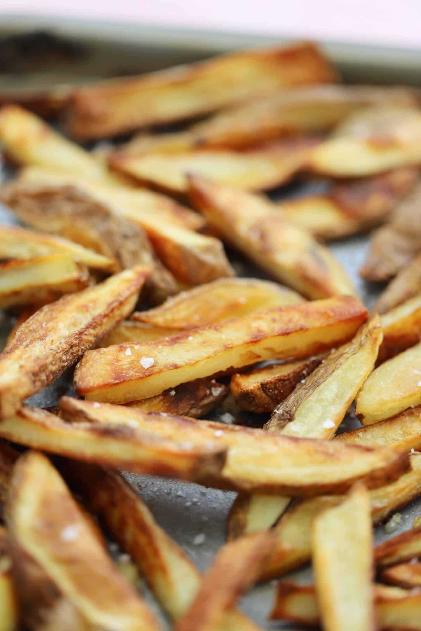 Close up of homemade oven chips on a tray.