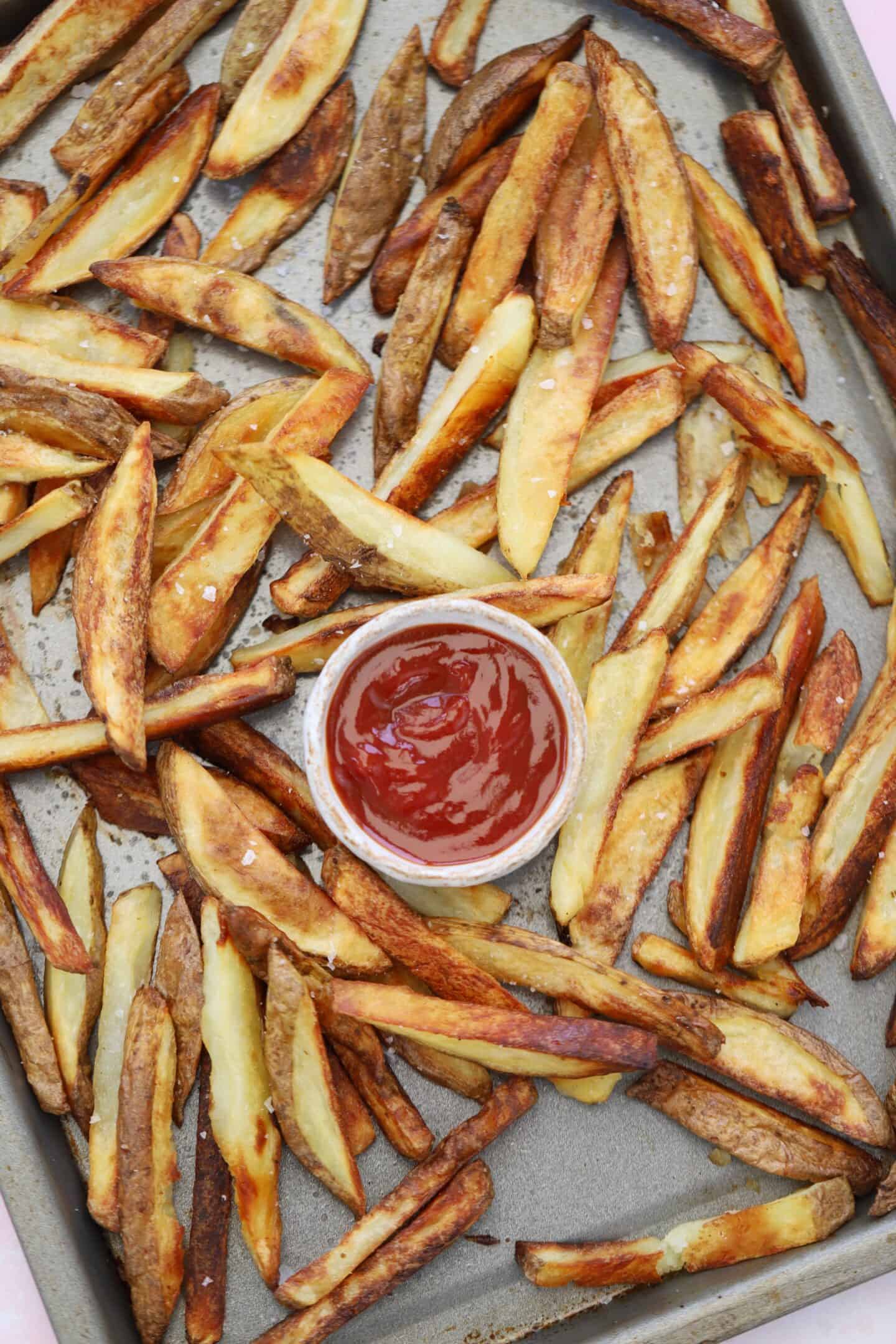 A tray of skin on fries with tomato ketchup.