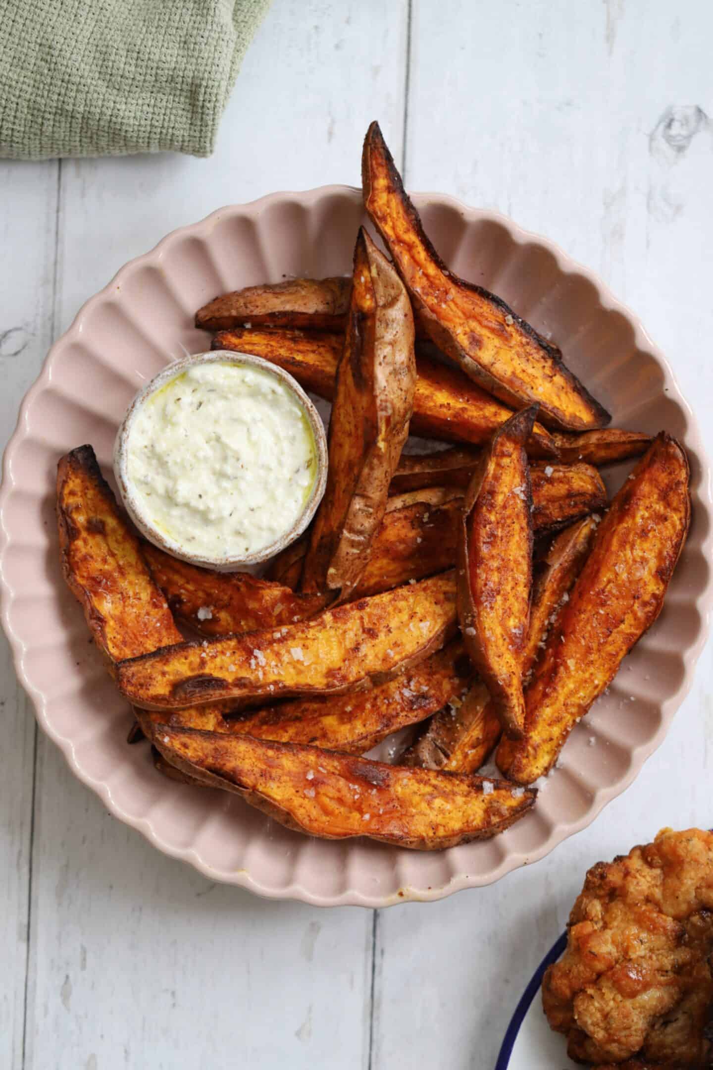 A bowl of air fried sweet potato wedges with garlic dip.