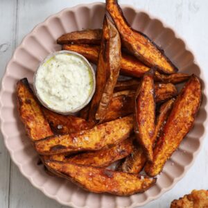 A bowl of air fried sweet potato wedges with garlic dip.