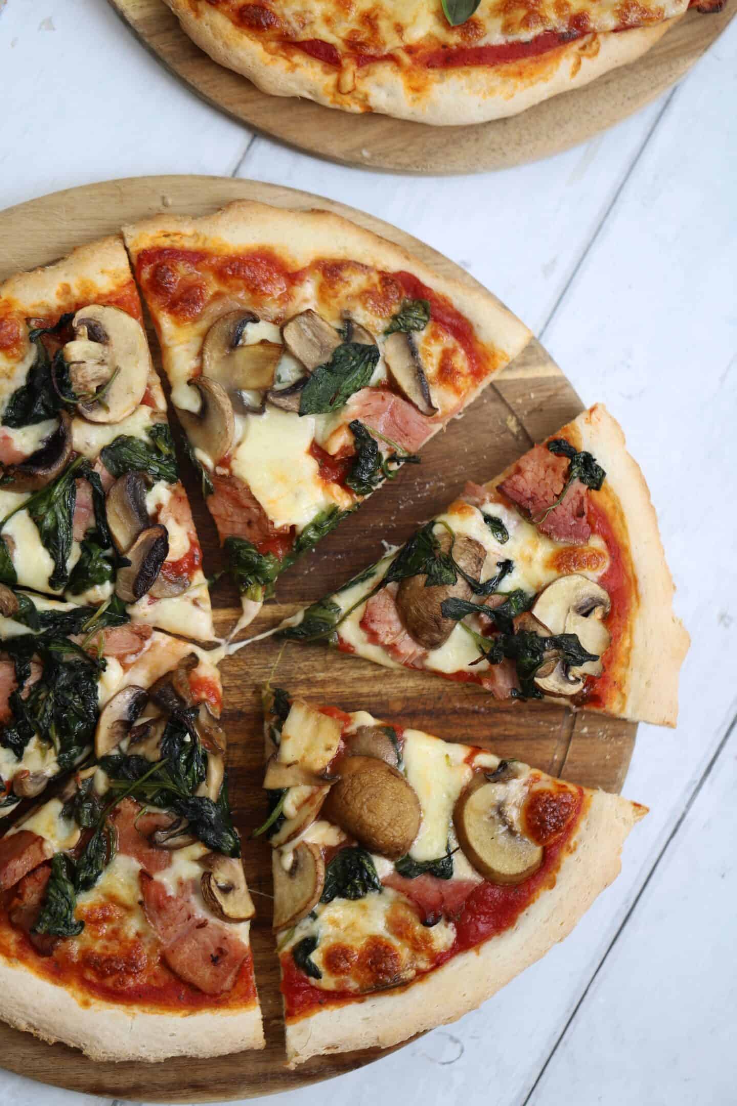 A gluten free pizza with mushroom, ham and spinach.