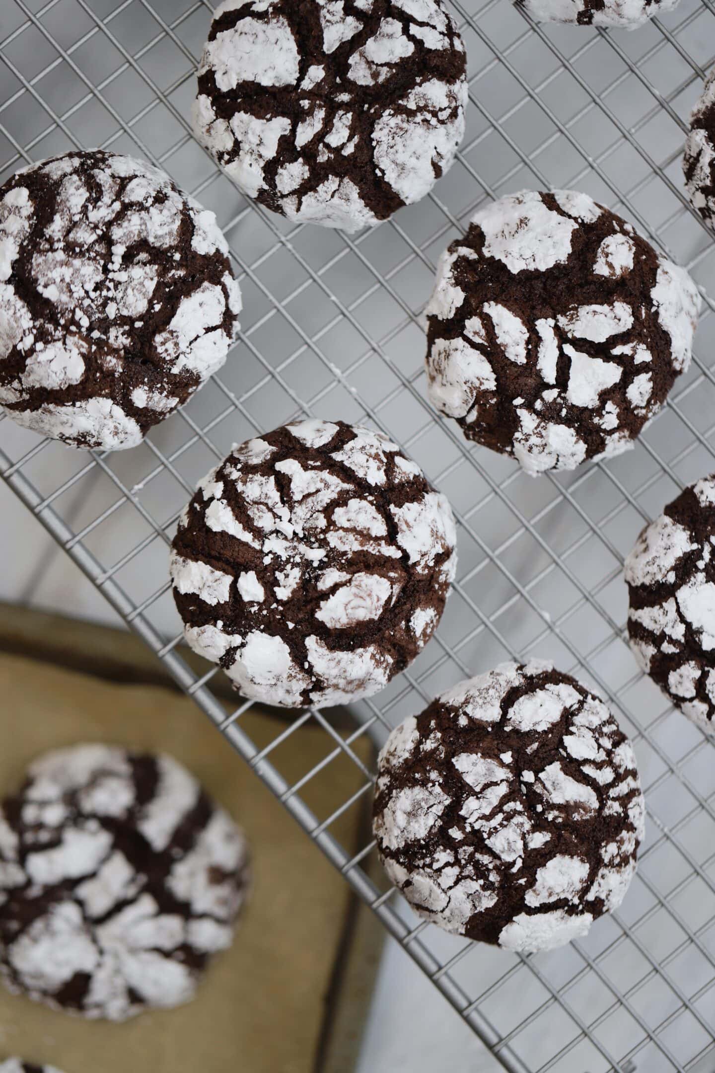A wire cooling rack with chocolate crinkle cookies on top.