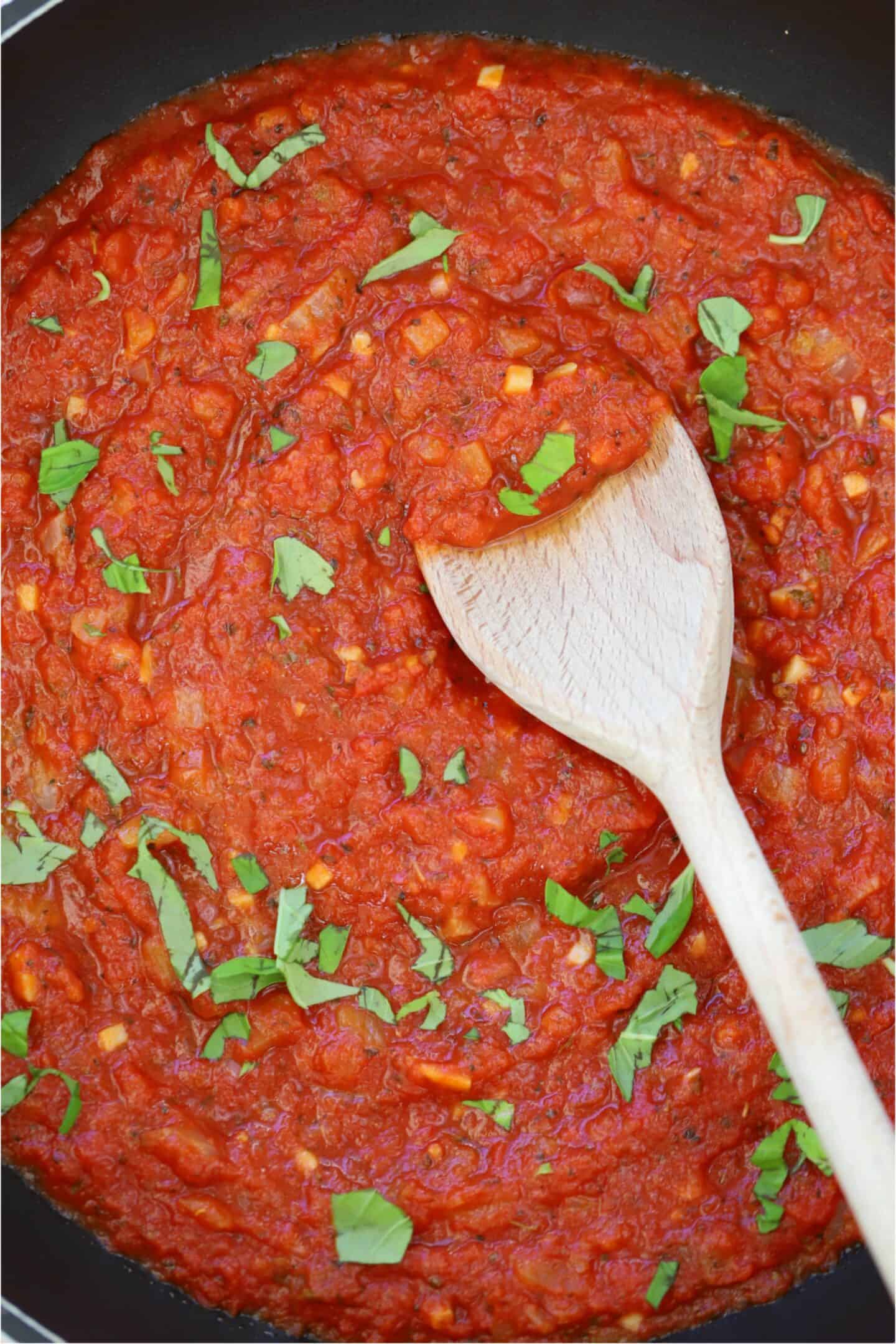 A pan of gluten free marinara sauce with a wooden spoon.