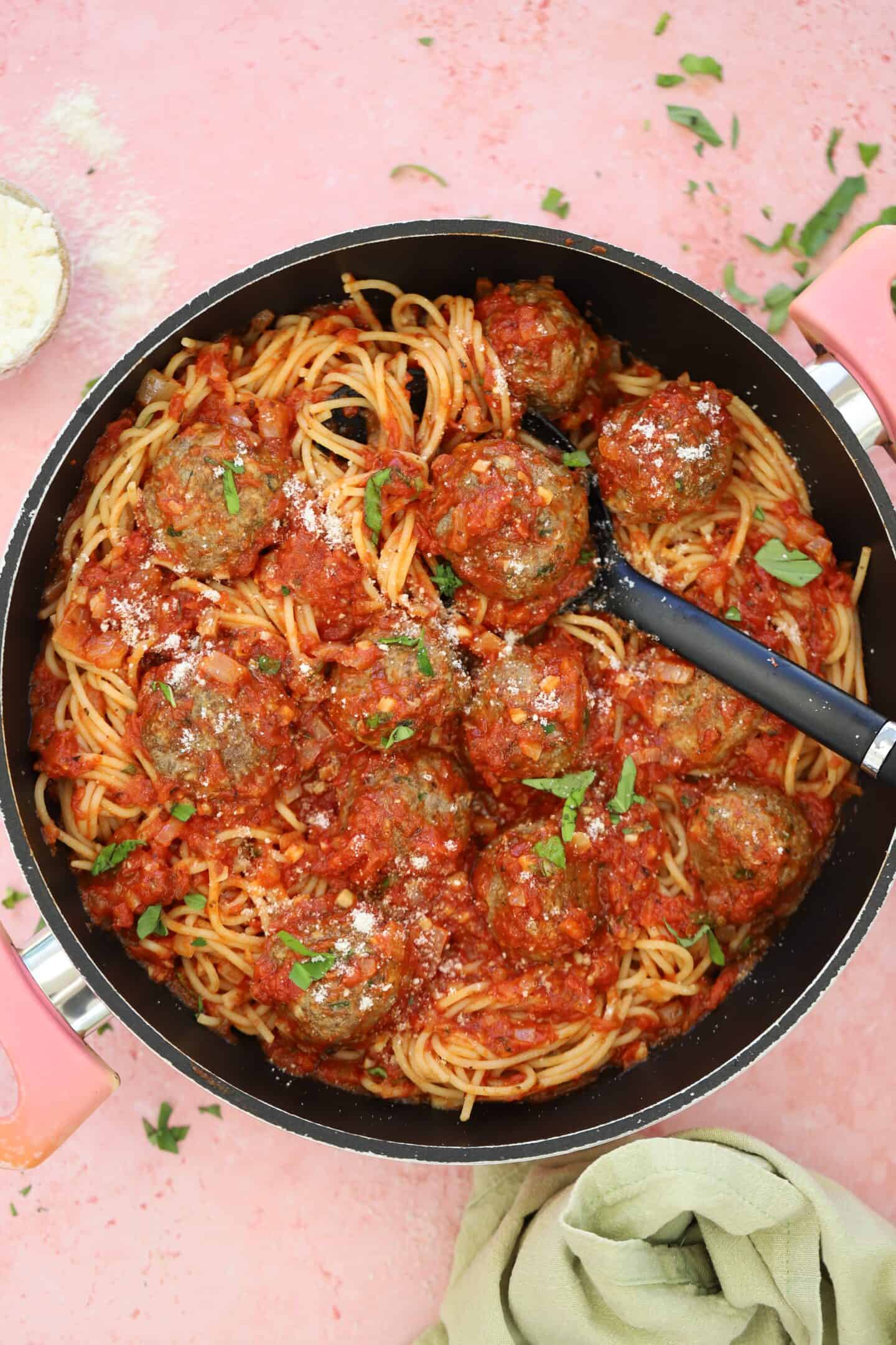 A pan of gluten free beef meatballs with spaghetti and sauce.