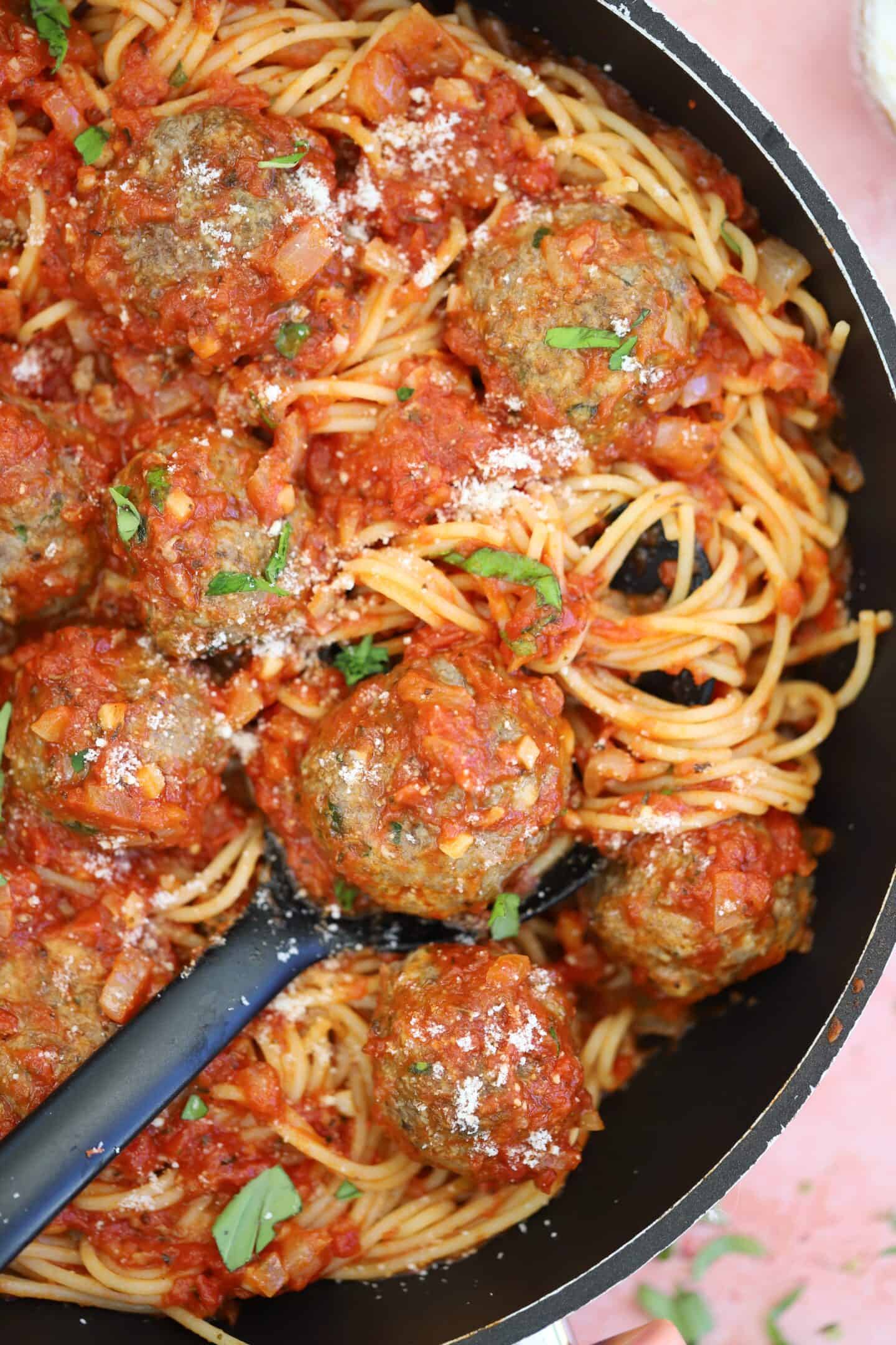 A pan of gluten free meatballs in sauce with spaghetti.