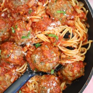 A pan of gluten free meatballs in sauce with spaghetti.