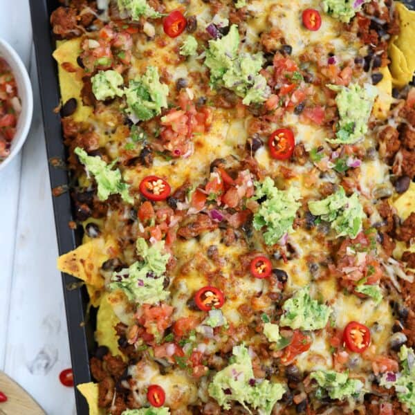 A tray of gluten free nachos with beef, cheese, guacamole and salsa.