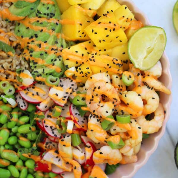 A prawn poke bowl with mango, avocado and veg with sriracha sauce.