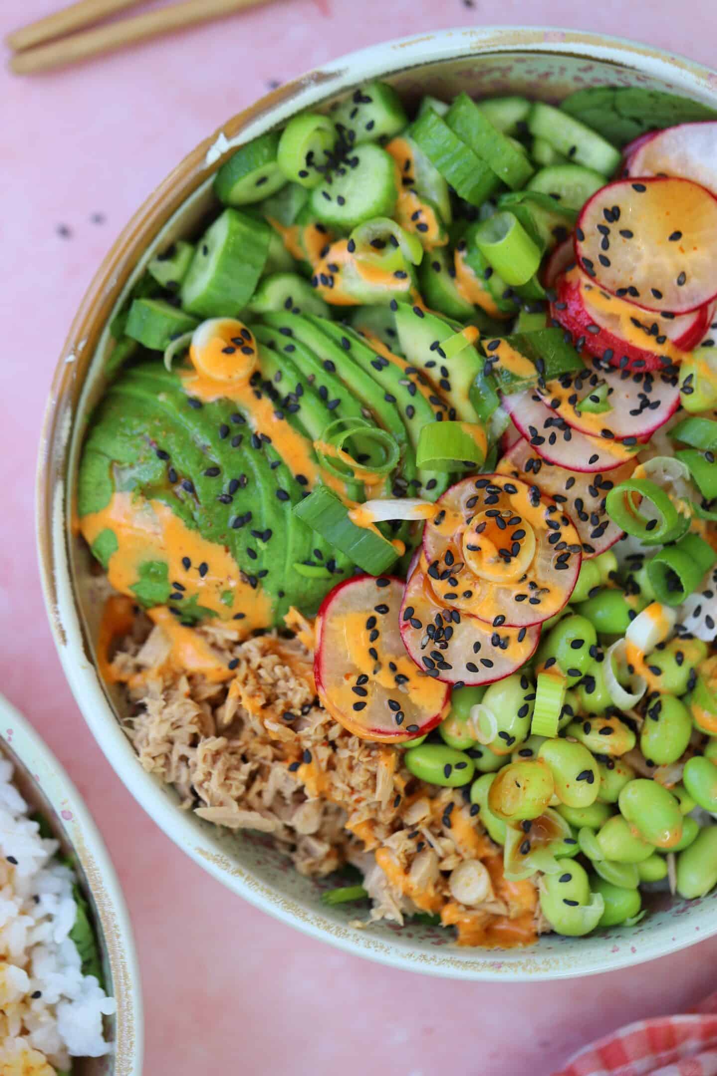 Close up of a tuna sushi bowl with edamame beans, avocado and spicy mayo sauce.