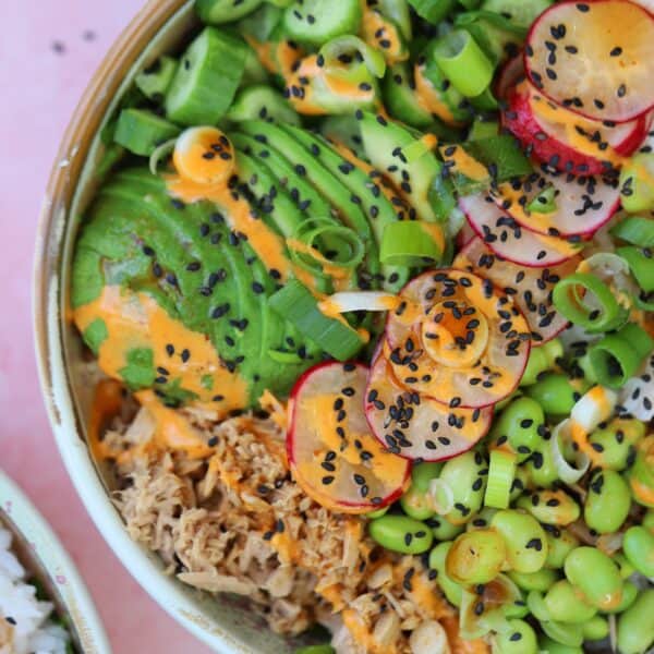 Close up of a tuna sushi bowl with edamame beans, avocado and spicy mayo sauce.