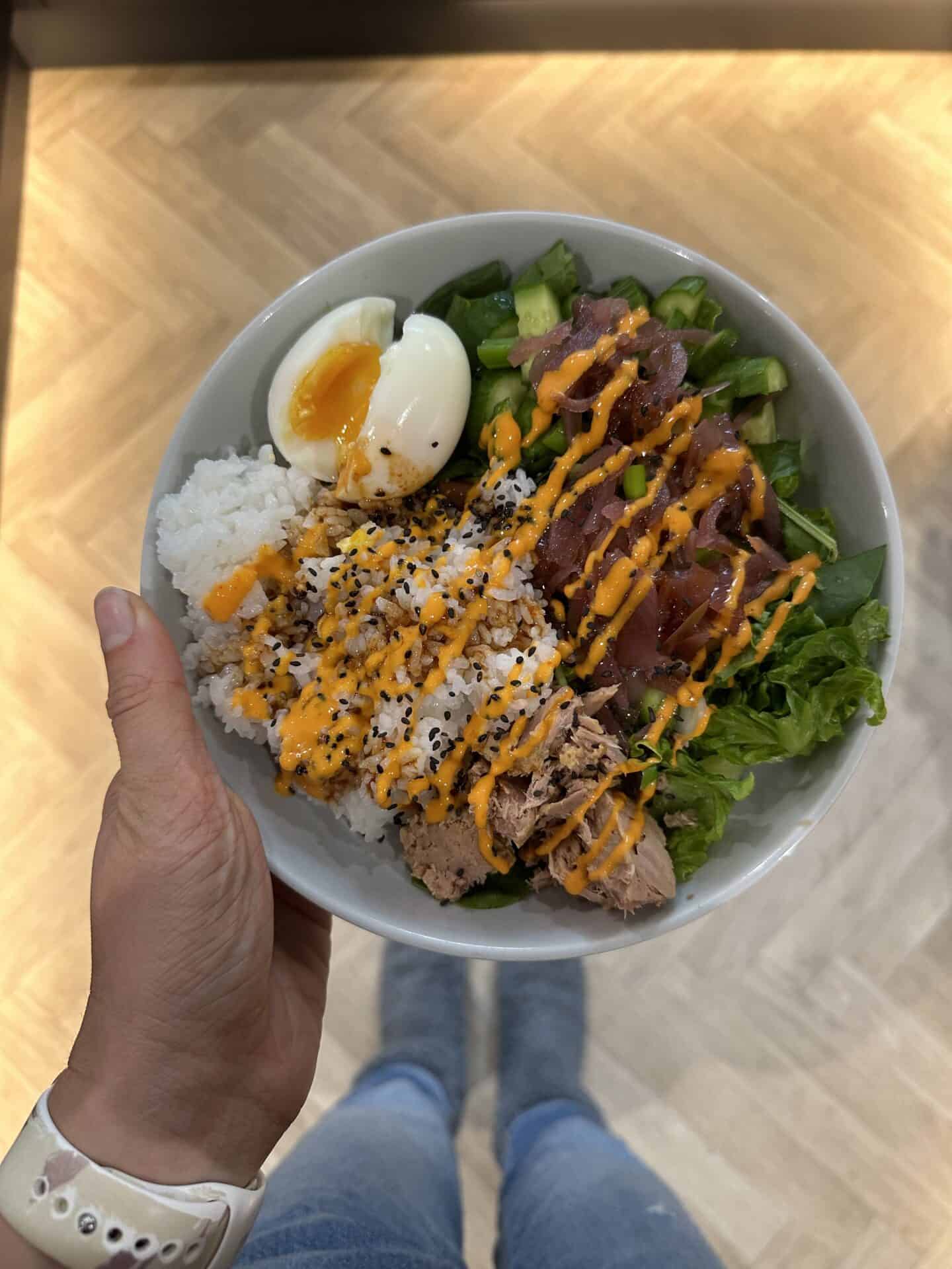 A tuna sushi bowl with pink pickled onions and a boiled egg.