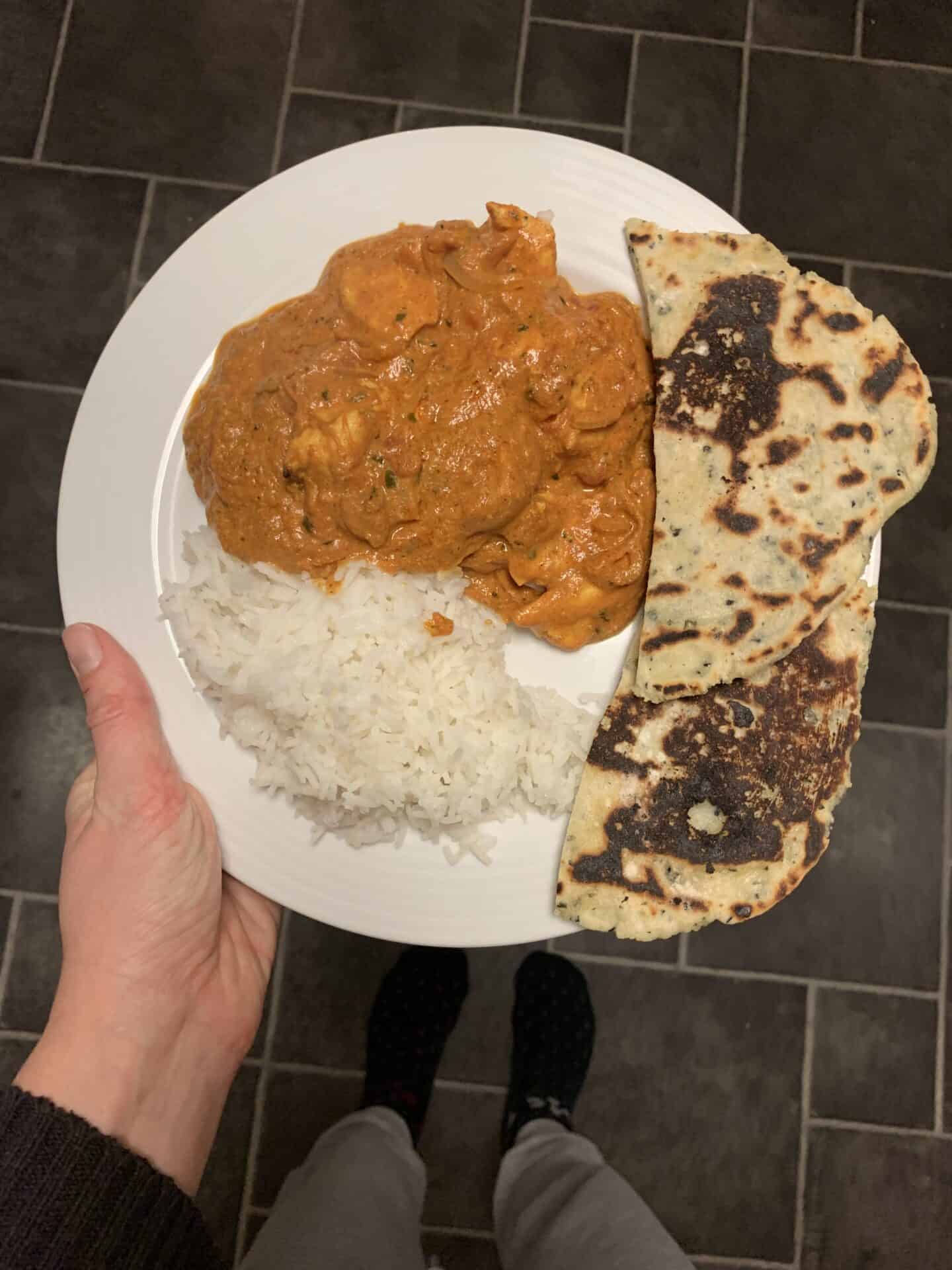 A naan bread with a butter chicken curry.