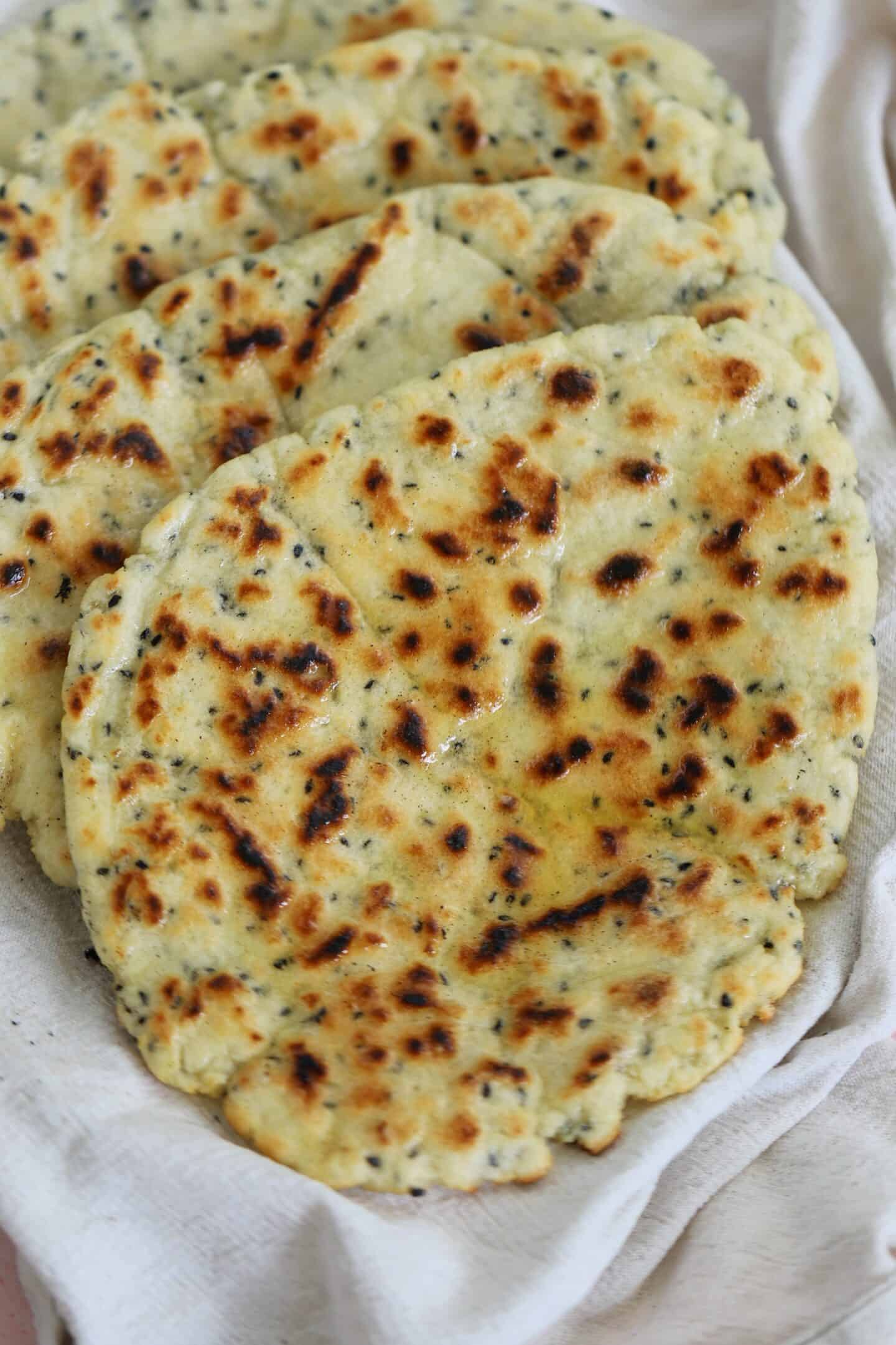 Gluten free naan breads wrapped in a tea towel.