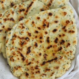 Gluten free naan breads wrapped in a tea towel.