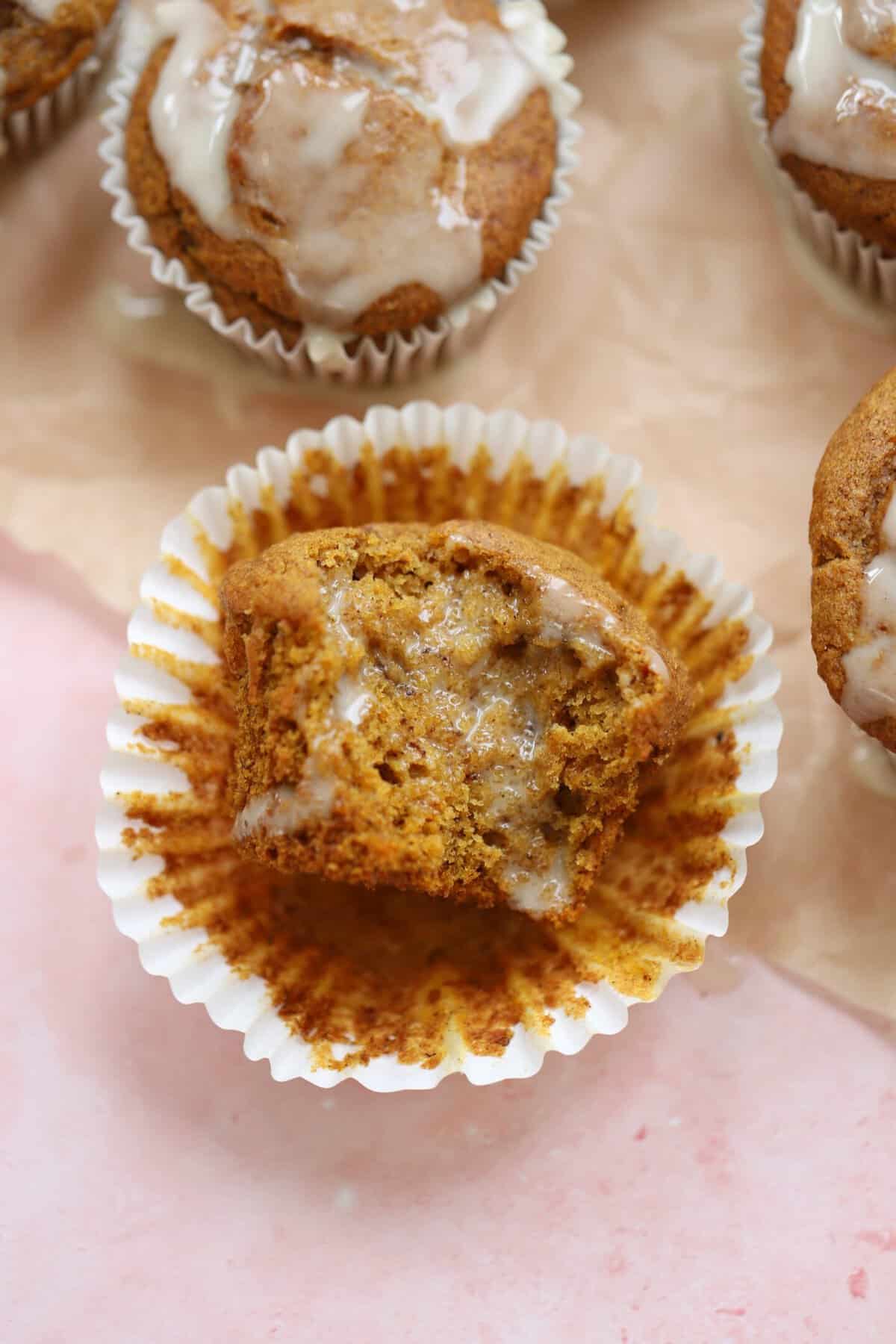 Gluten free pumpkin banana muffins with maple glaze on a sheet of parchment paper.