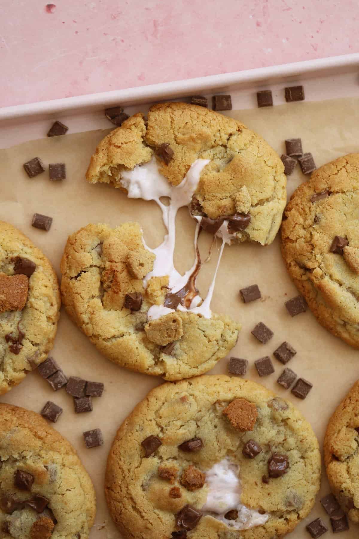 A gluten free s'mores cookie broken in half surrounded by chocolate chips.