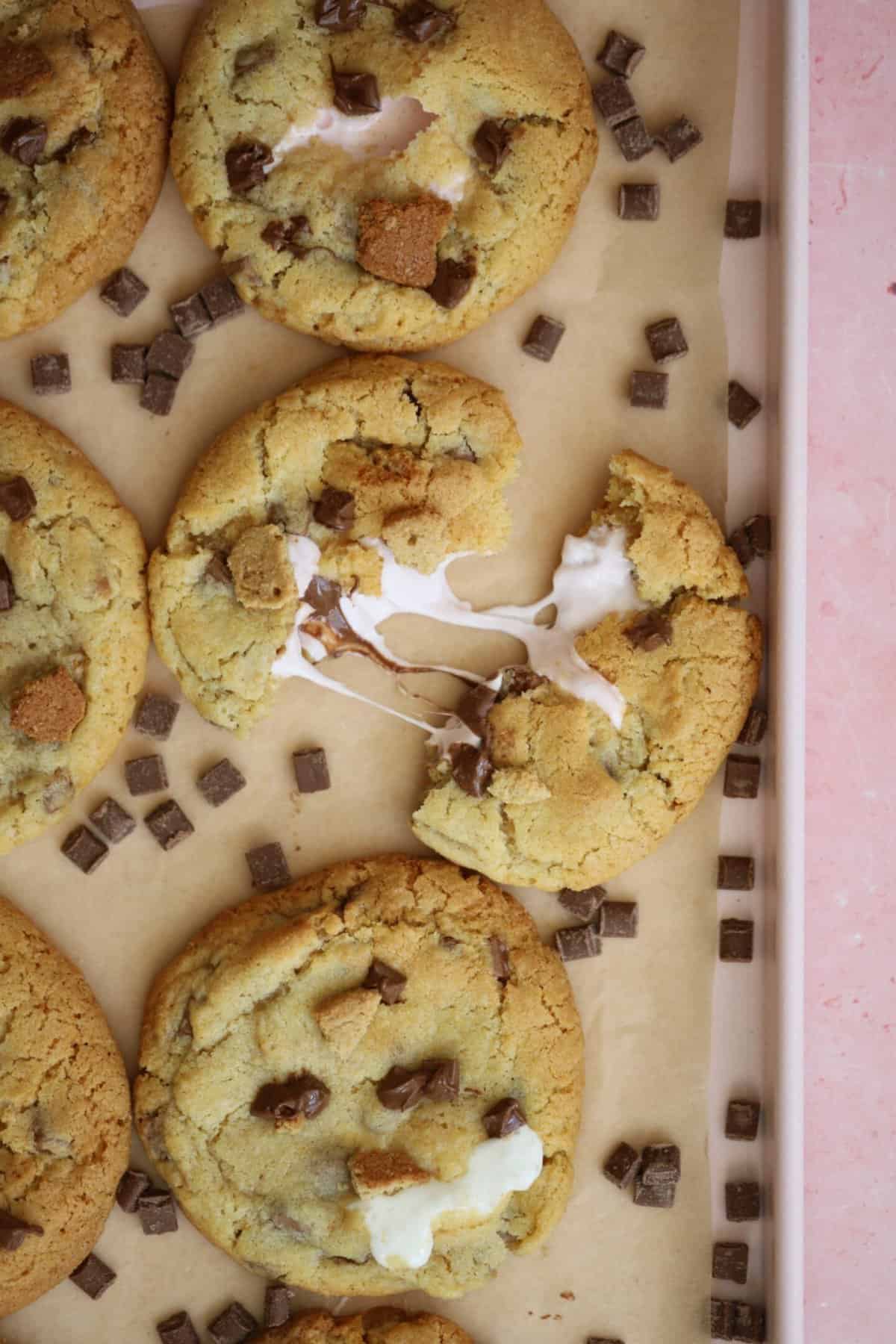 A gluten free s'mores cookie broken in half surrounded by chocolate chips.