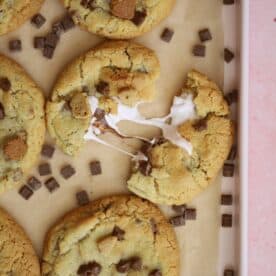 A gluten free s'mores cookie broken in half surrounded by chocolate chips.