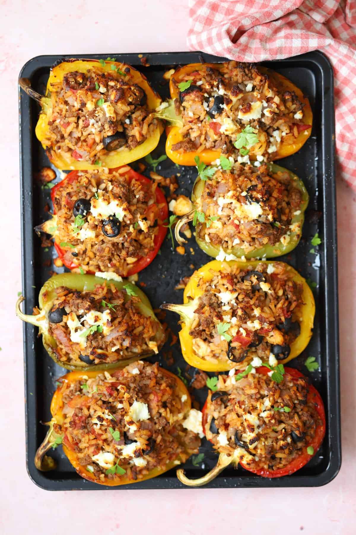 A tray of gluten free stuffed peppers on a pink background.