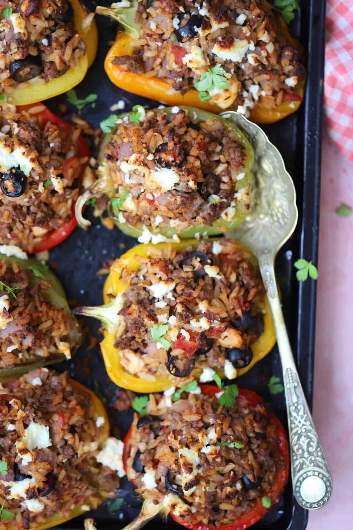 A tray of gluten free stuffed peppers with a spoon.