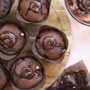 Gluten free triple chocolate muffins with a chocolate ganache filling on a wooden chopping board.