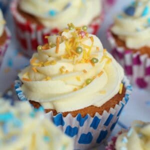 A gluten free vanilla cupcake with orange and yellow sprinkles.