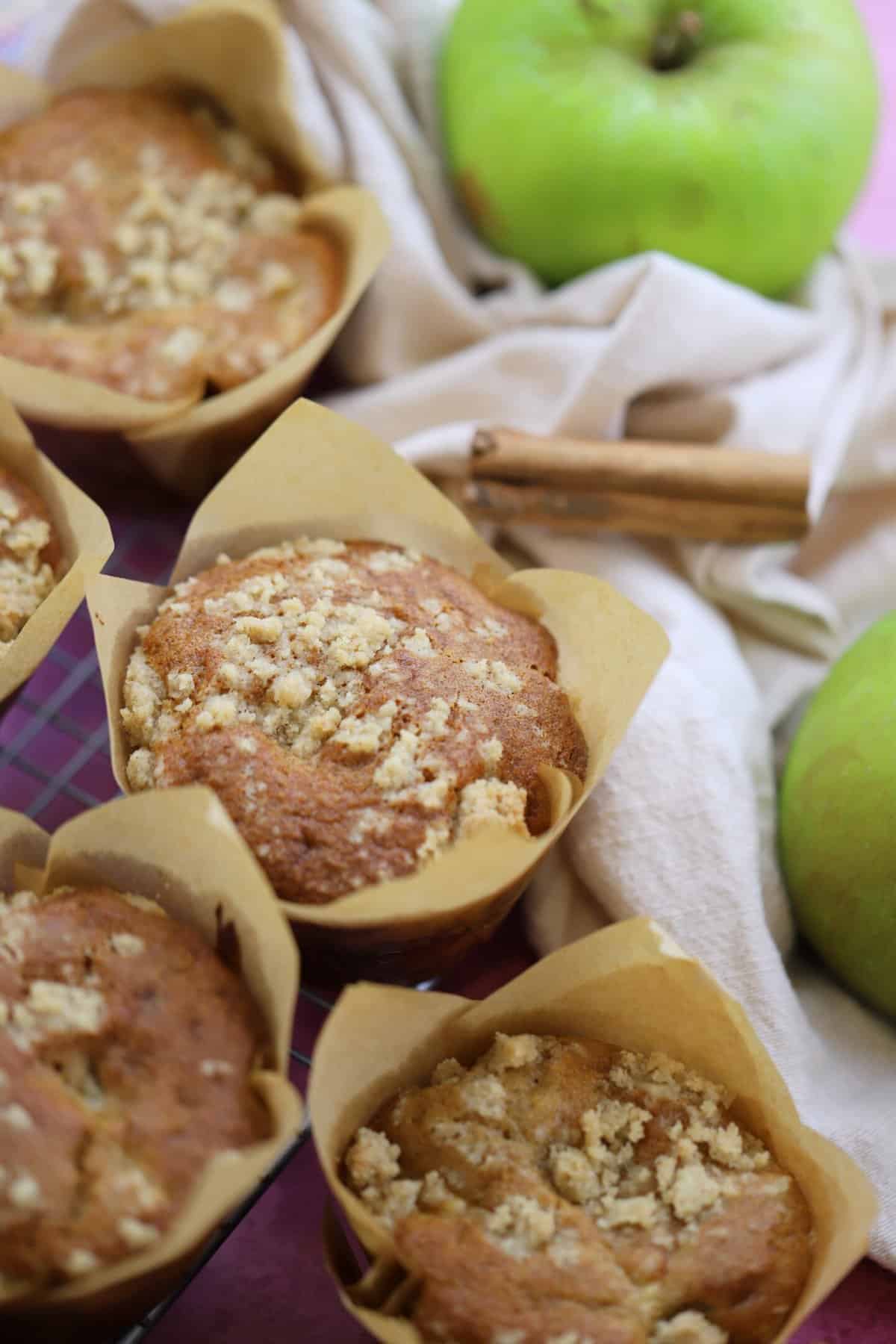 Gluten free apple muffins with an apple and cinnamon stick behind.