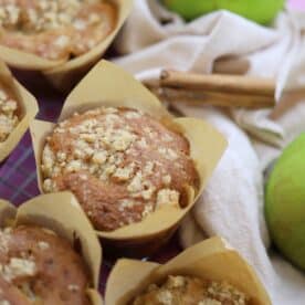 Gluten free apple muffins with an apple and cinnamon stick behind.