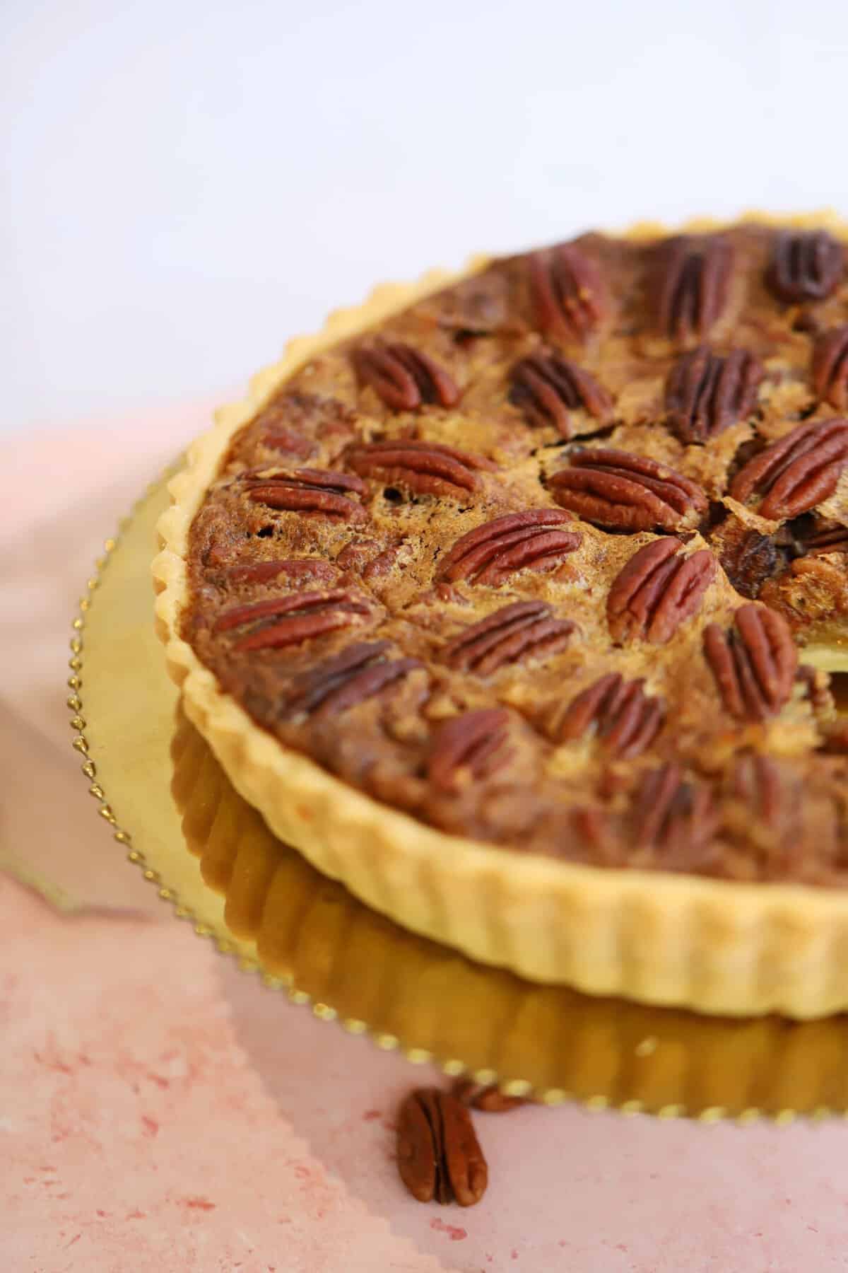 A gluten free pecan pie on a gold plate.