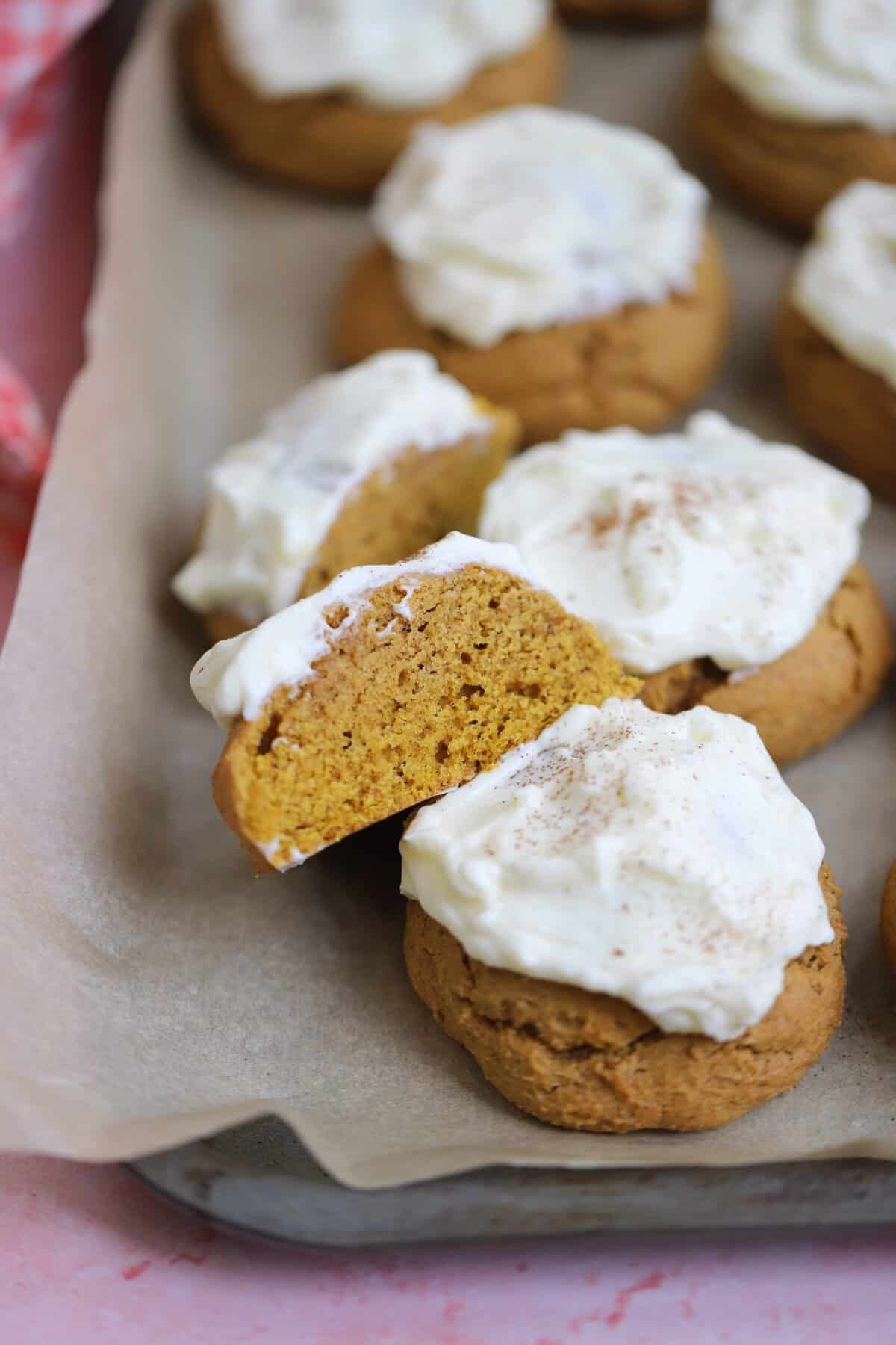 A baking tray with soft gluten free pumpkin cookies and cream cheese frosting.