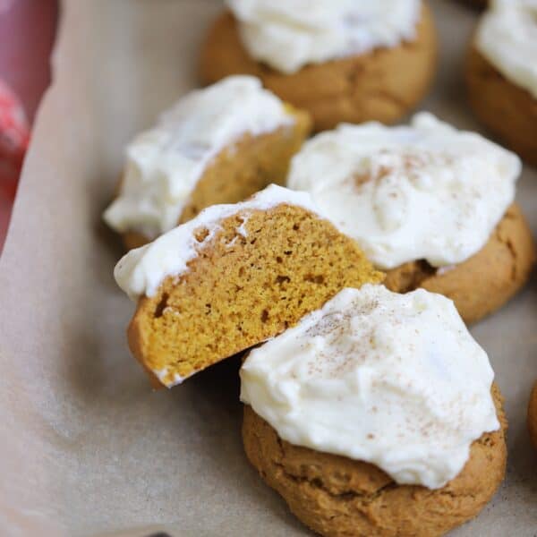 A baking tray with soft gluten free pumpkin cookies and cream cheese frosting.