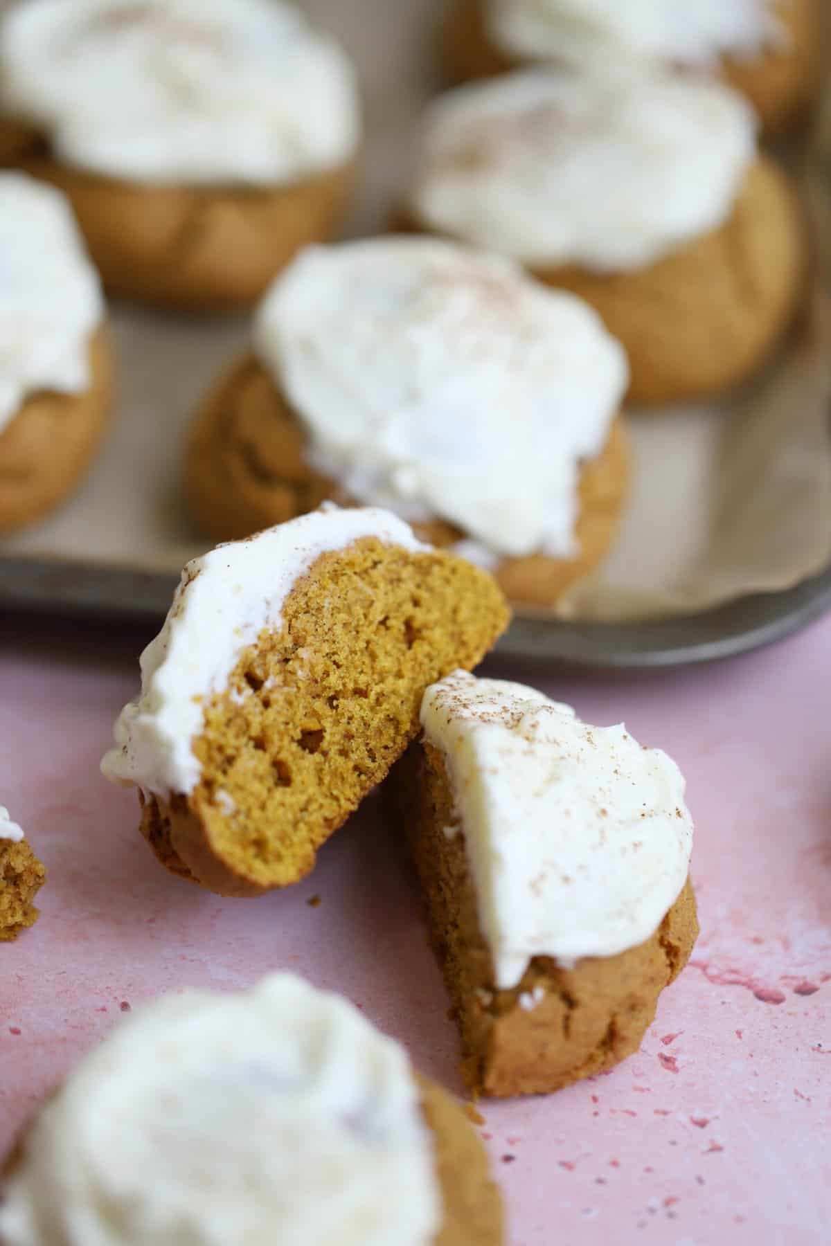 A baking tray with soft gluten free pumpkin cookies and cream cheese frosting.