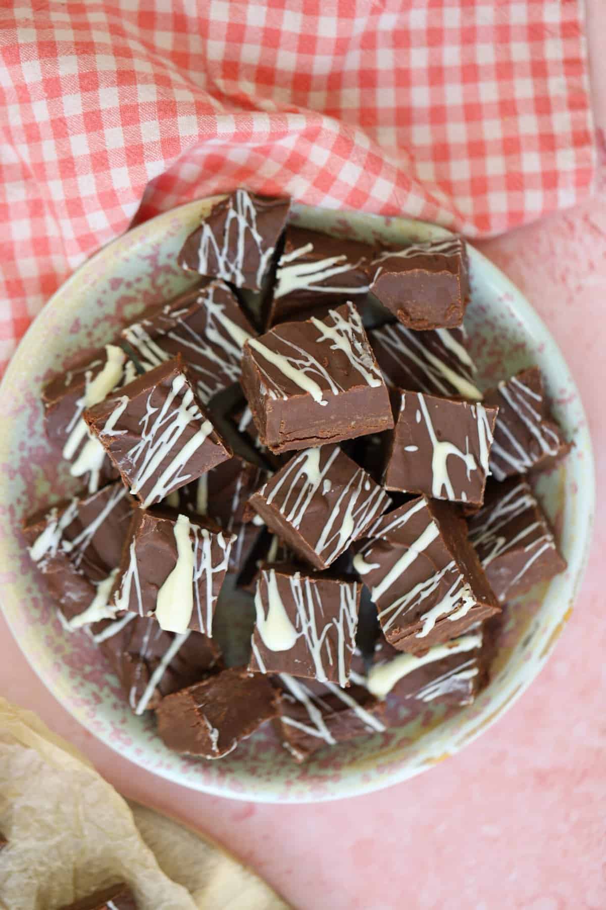 Overhead shot of a plate of slow cooker fudge on a pink worktop.