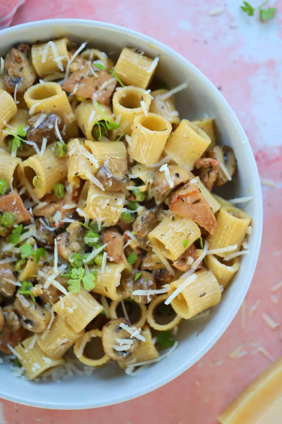 Close up of a bowl of creamy ham and mushroom pasta.